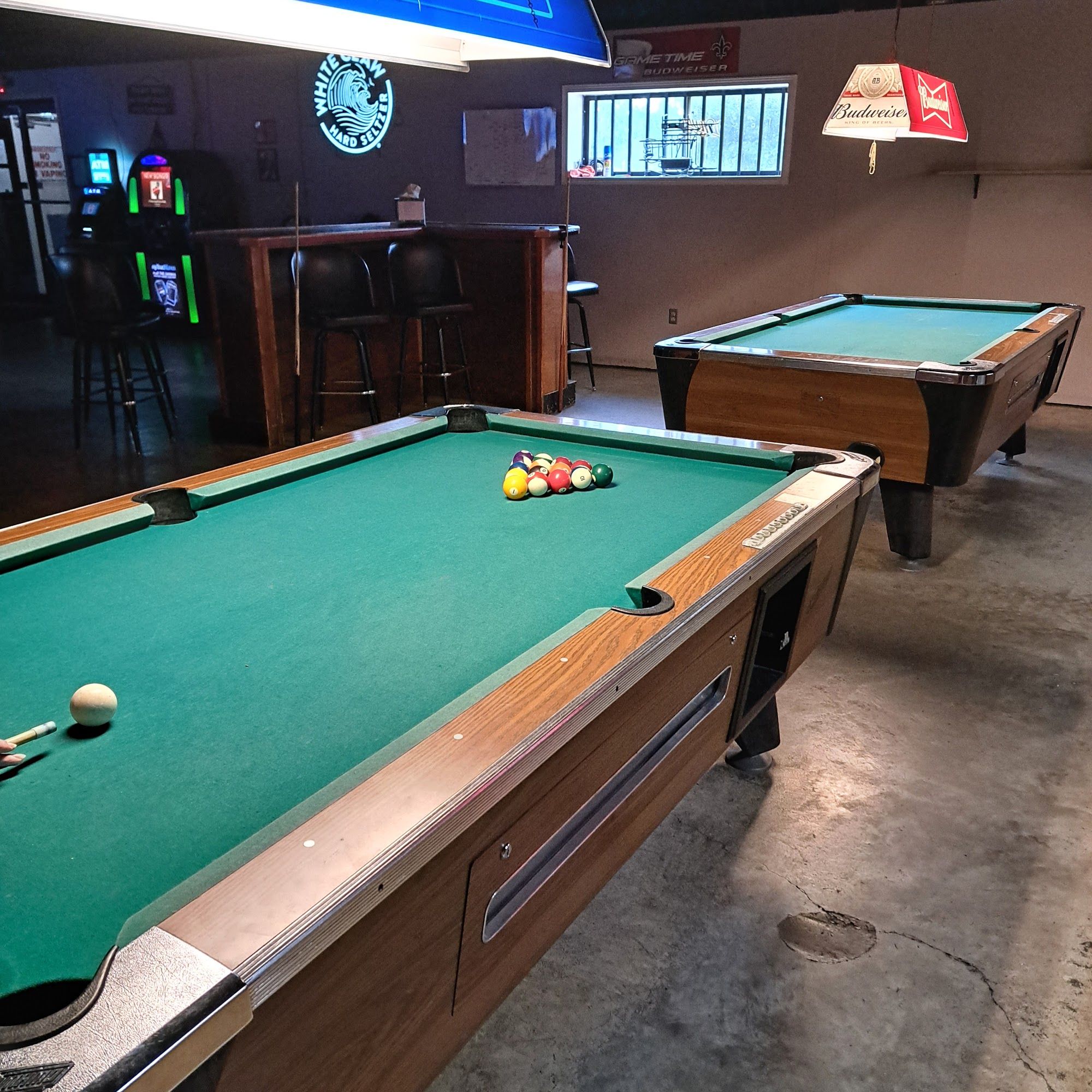 Two green-felt pool tables under a hanging lamp inside Big's Place