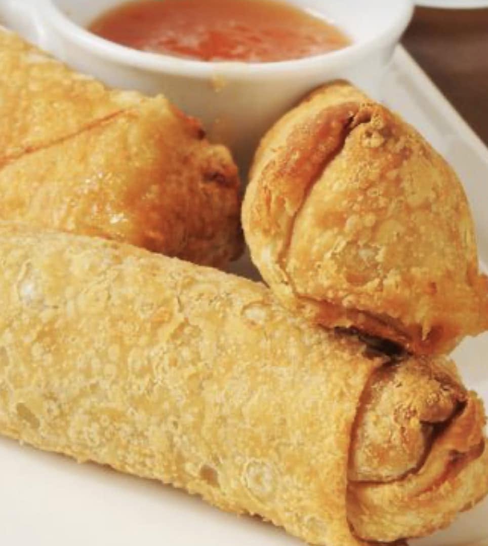 Golden fried spring rolls with a bowl of orange dipping sauce