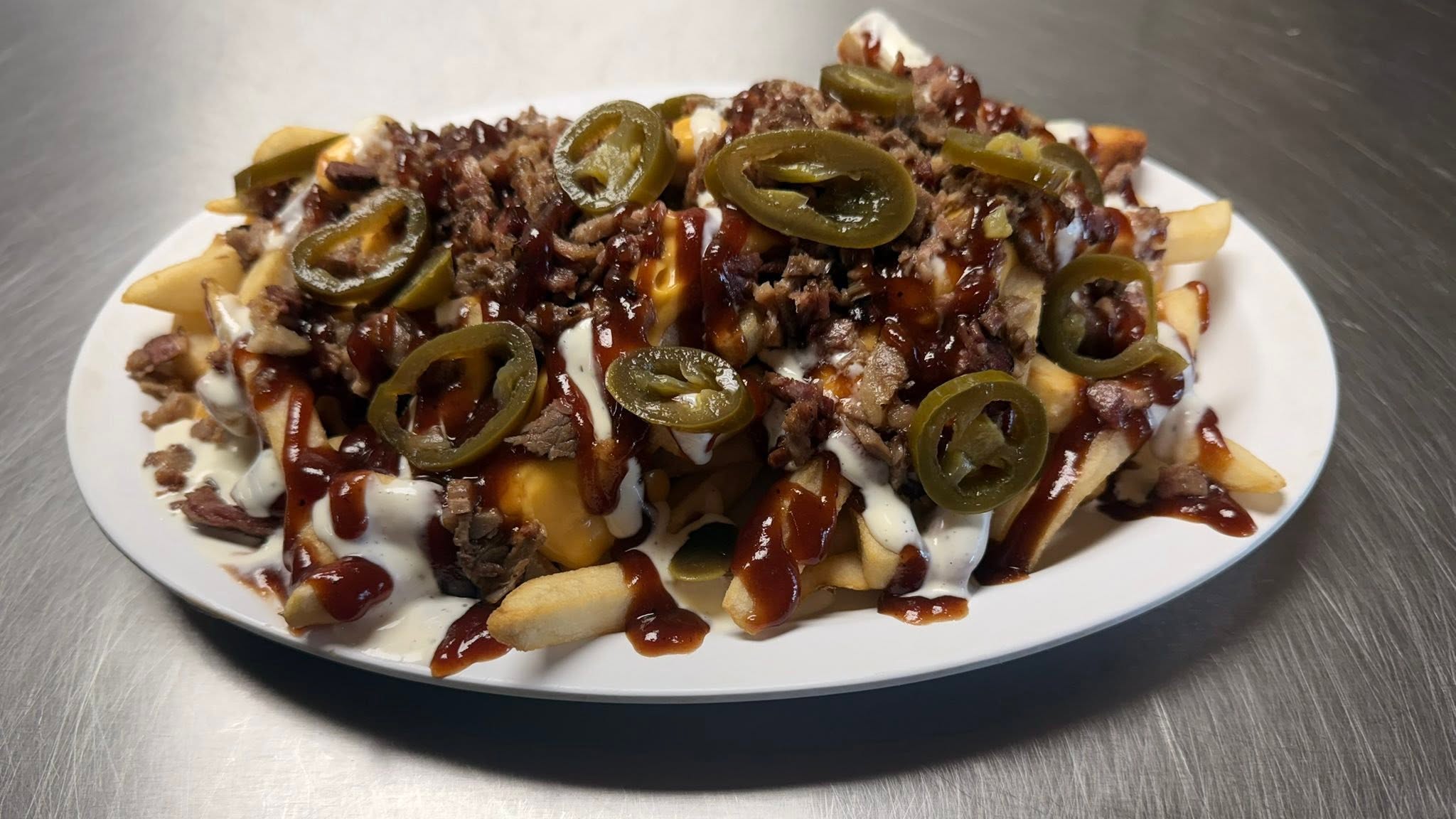 Loaded fries topped with meat, sauces and sliced jalapeños